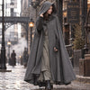 Femme portant le manteau cape vintage gris, capuche relevee, rue pavee steampunk