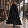 Manteau cape vintage noir vu de dos, longue cape a capuche, decor de gare steampunk