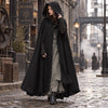 Femme portant le manteau cape vintage noir, capuche relevee, rue pavee steampunk